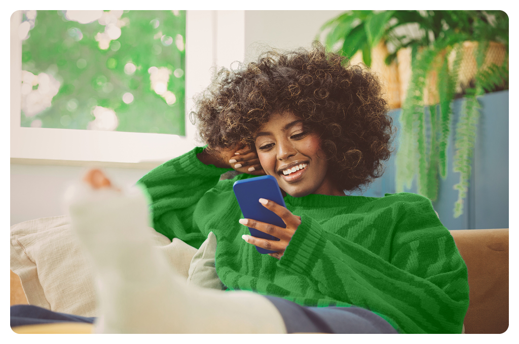 Woman in green sweater smiling at her cellphone